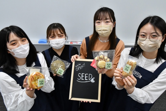 ＮＰＯ団体と共同開発したパンを手にするシードのメンバー＝中村区の愛知大名古屋キャンパスで