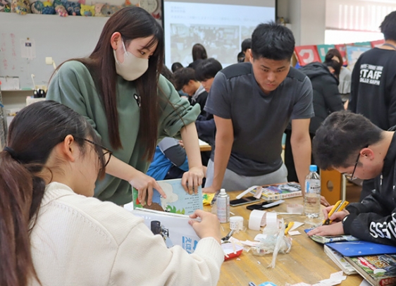 カッターや接着剤を使って絵本を修理する学生たち＝尾張旭市新居町の名古屋経営短大で
