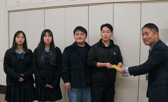 立花副施設長（右端）に寄付金を渡した（左から）緑丘高の３年生２人、松田さん、大曲さん＝港区で