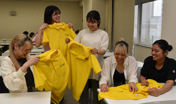 活動で使うポロシャツを手にする大橋さん（左から２人目）や八木さん（同３人目）らサークルのメンバー＝名古屋市中区で