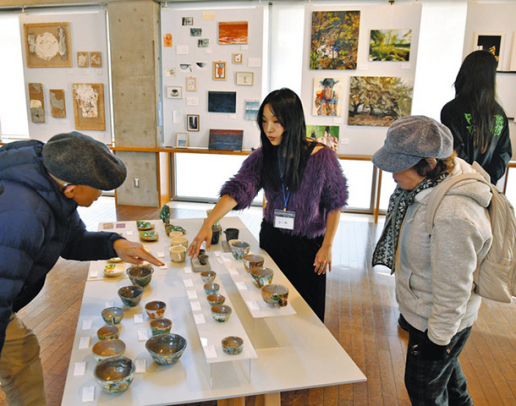 展示販売の会場で、来場者に自身の作品について解説する学生(中)ら=愛知県長久手市の文化の家で