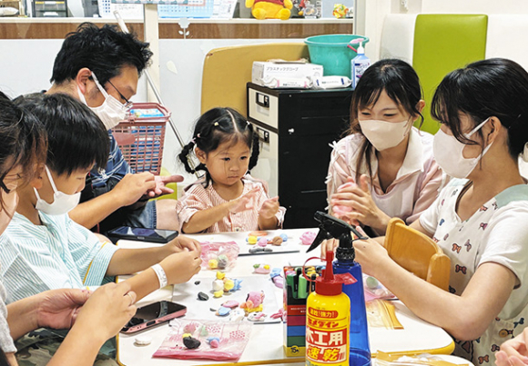 学生たちと粘土のマグネット作りを楽しむ子どもら=豊明市の藤田医科大病院で