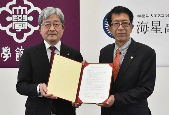 協定書を手にする皇学館大の河野学長（左）と海星高の服部校長＝伊勢市の皇学館大で