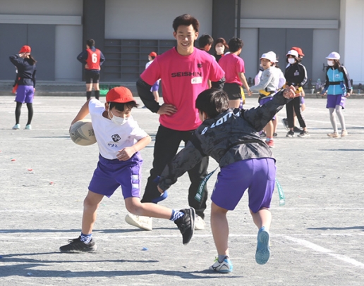 誠信高生の指導でタグラグビーを楽しむ児童たち=扶桑町の扶桑東小で