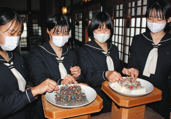 授業で使った針をこんにゃくと豆腐に刺す生徒たち＝一宮市の真清田神社で