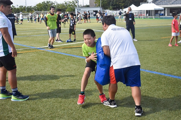 果敢なタックルを見せる児童＝春日井市朝宮町４のスポーレ春日井で