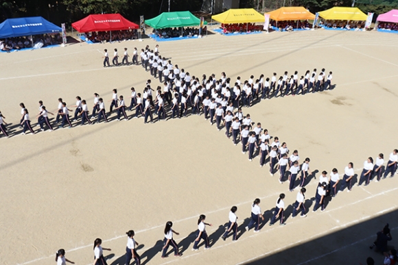 十字などさまざまな形をつくりながら行進する生徒たち＝瀬戸市西長根町の聖カピタニオ女子高で