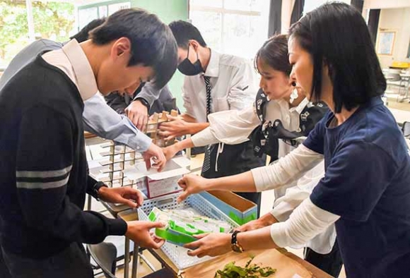 大林さん（右端）、蓮尾さん（右から２人目）と繭を取り出す生徒たち