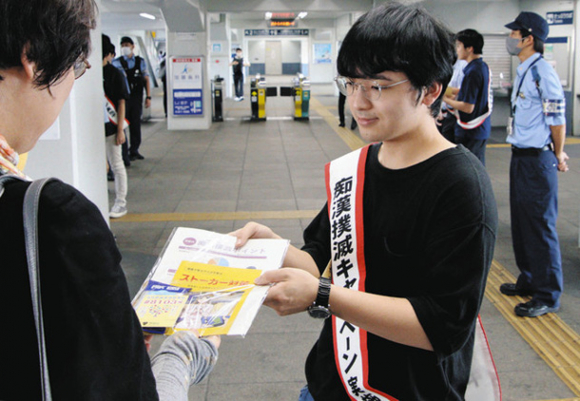 駅の利用者に啓発チラシなどを手渡す学生ら＝南区の大同町駅で