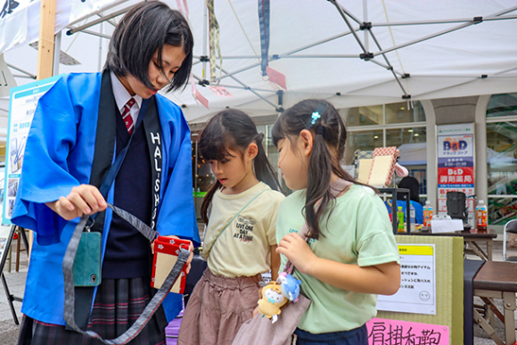 畳のへりを使って開発した商品を紹介する生徒（左）＝春日井市の勝川駅前公園で