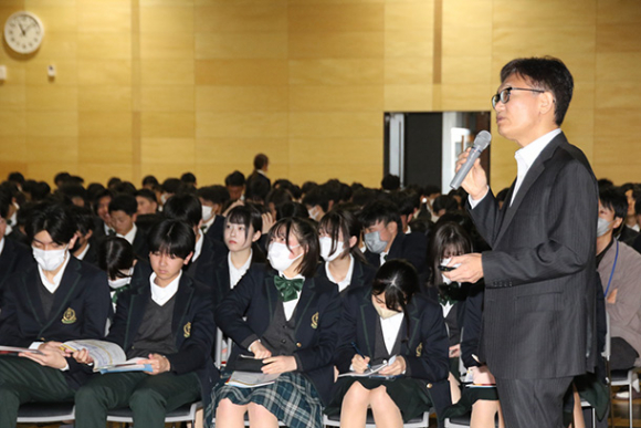 酒井さん（右）の話に耳を傾ける生徒ら＝四日市市の海星高で