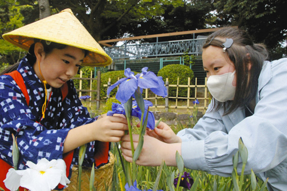 子どもに摘み取り方を指導する生徒(右)=名古屋市昭和区の鶴舞公園で