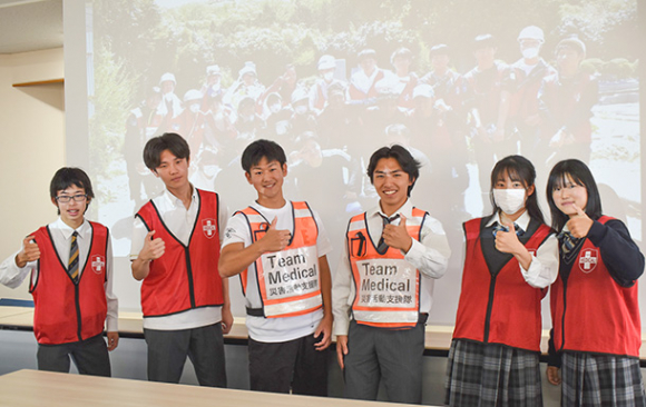 親指で能登半島を表現する生徒ら。多くの人の被災地支援を呼びかけている=千種区の愛知高で
