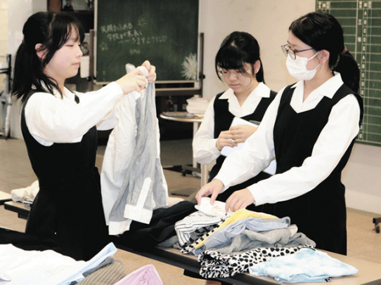 長机に並んだ服を手に取る生徒たち=昭和区の南山高・中女子部で