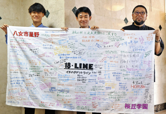 残り火を守る関係者からのメッセージが書き込まれた横断幕を掲げる生徒ら=豊橋市の桜丘学園で