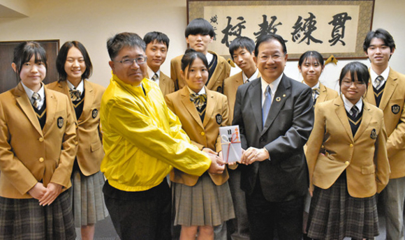 山崎理事長（前列右から２人目）に目録を手渡す生徒ら＝津市の高田高で