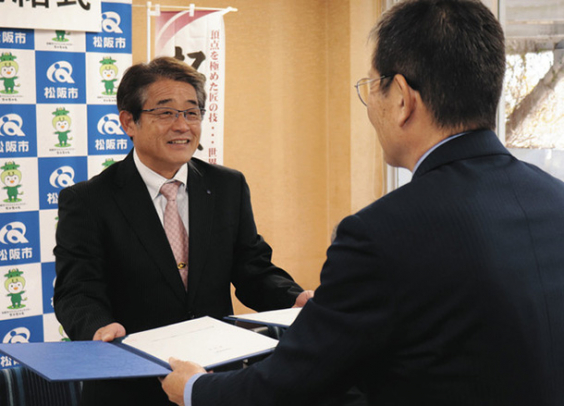 協定書を取り交わす竹上市長（手前）と神崎校長＝松阪市役所で