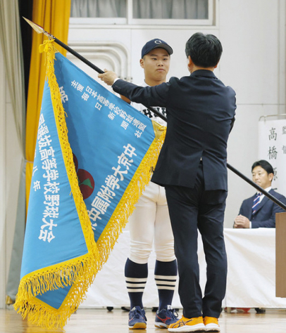 伊藤校長（手前）から選抜旗を渡される主将＝名古屋市昭和区で