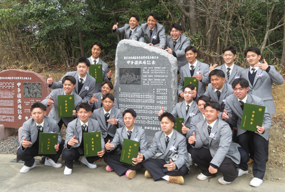 昨夏の甲子園出場の記念碑で集合写真を撮る津田学園高の3年生たち=桑名市野田の同高野球場で