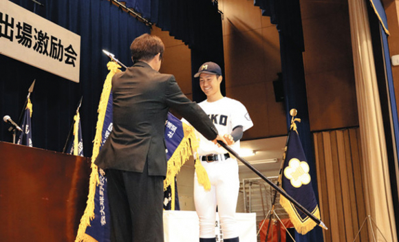 神崎校長（手前）から選抜旗を受け取る大西主将＝松阪市久保町の三重高で