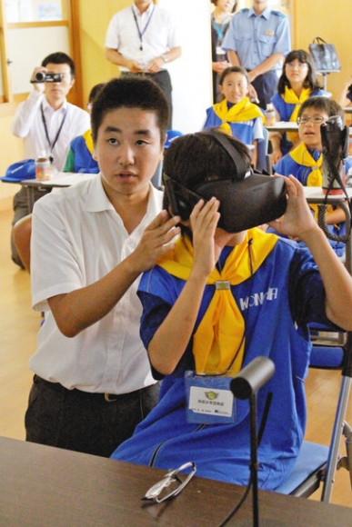 愛工大名電高生のサポートを受けながらＶＲのゴーグルを着用し、教材を体験する子ども＝大口町の大口北小で