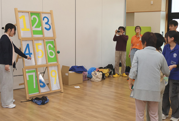 高校生と的当てを楽しむ参加者＝春日井市高森台の「たかもり」で