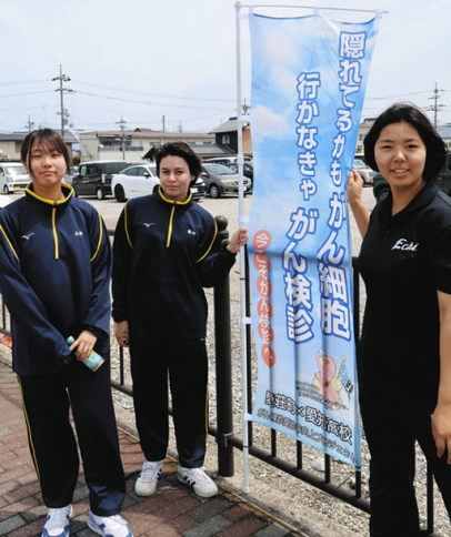 がん検診受診を促すのぼり旗を設置する愛知高の生徒たち＝愛荘町愛知川で