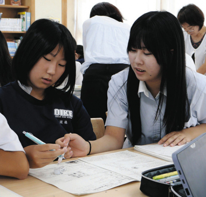 高校生（右）に勉強を教えてもらう中学生＝四日市市の大池中で