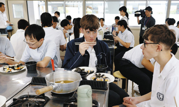 すしやみそ汁を食べて交流する生徒たち＝伊勢市の皇学館中で
