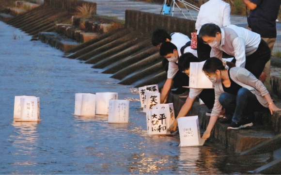 灯籠を豊川に流す集会参加者＝豊橋市湊町で