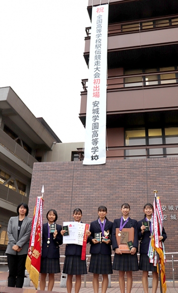 懸垂幕の前で活躍を誓う陸上競技部の部員ら＝安城市役所で