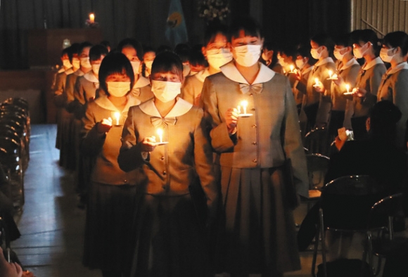 「世の光になるように」との願いを込めたろうそくの明かりを手に退場する卒業生=岐阜市の聖マリア女学院高で