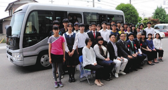 寄贈されたマイクロバスと記念撮影する生徒や保護者ら＝岐阜市の岐阜東中学・高校で