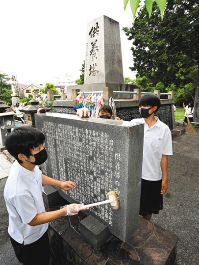 大空襲の供養塔を清掃する豊川高の生徒たち。左は生徒会長の鈴木さん＝７日、愛知県豊川市で（太田朗子撮影）