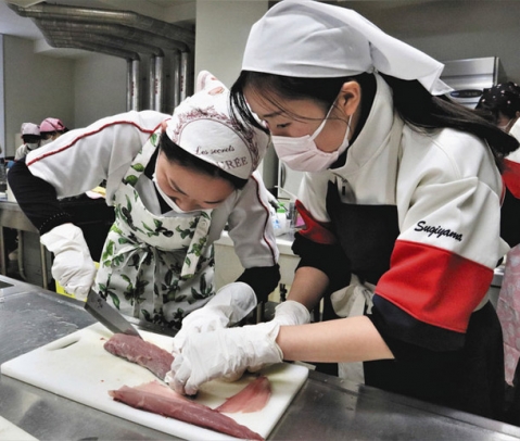 真剣な面持ちでツバスを三枚におろす生徒＝千種区山添町２の椙山女学園高で