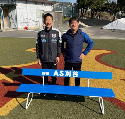 寄贈したベンチを前にするＡＳ刈谷の浜島監督（左）と、星城高サッカー部の大木監督＝豊明市の星城高グラウンドで