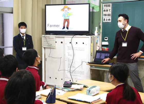 中学生たちに英語を教える愛知啓成高の生徒（左）と外国人講師＝稲沢市稲沢西中で