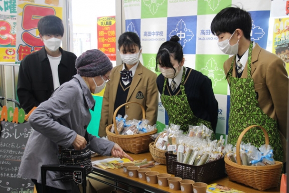 地域の人たちにウガンダ産のカカオ豆で作った洋菓子を販売する生徒たち＝津市新町１で