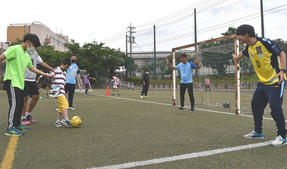 子どもたちとサッカーを楽しむ（右から）深川さん、大木監督とサッカー部員たち＝豊明市の星城高で