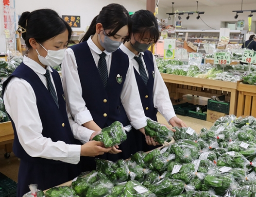 店に並ぶ新鮮な野菜を手に取る生徒たち＝岐南町三宅のＪＡぎふおんさい広場はぐりで