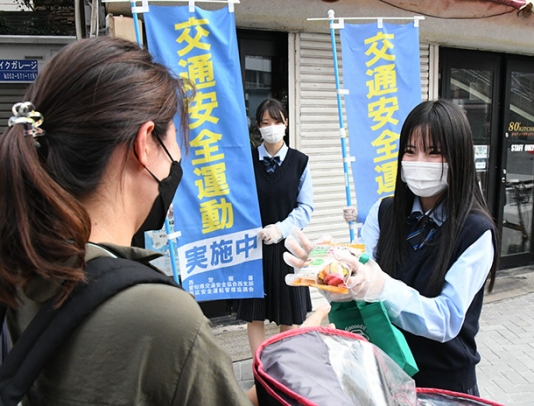 ランチパックを買い物客（左）に手渡す高校生＝名古屋市西区の円頓寺本町商店街で