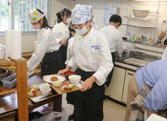 忙しそうに料理を作ったり、運んだりする生徒たち＝知多市緑町の市民活動センターで