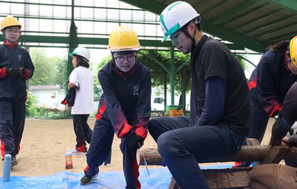 のこぎりでヒノキを切る生徒たち＝熊野市井戸町の「熊野の宿　海ひかり」で