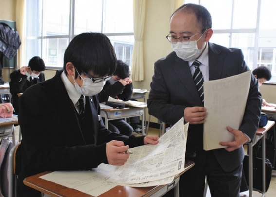 地震を報じた紙面を手にワークシートに取り組む生徒と中尾教諭（右）＝伊賀市下神戸で