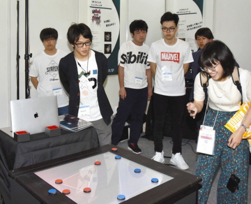 来場者（右端）にゲームを体験してもらう学生ら＝千葉市の幕張メッセで