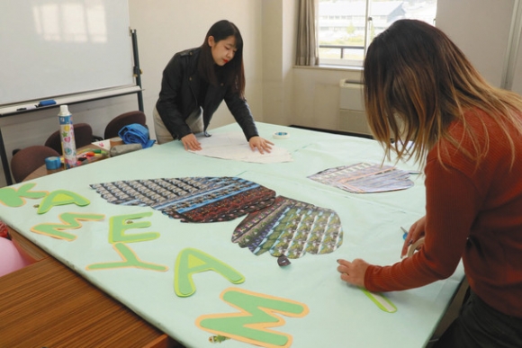 ブースの装飾を作製する学生たち＝亀山市関町木崎の亀山市関支所で