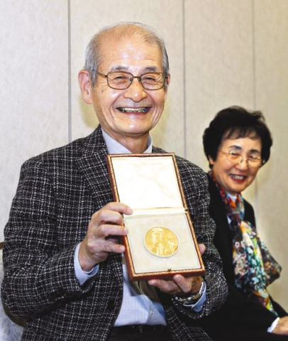  記者会見でメダルを披露する名城大教授の吉野彰さん。右は妻久美子さん＝１５日午前、成田空港で