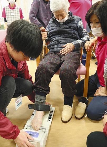 高齢者の足の指の握る力を測定する学生（左）＝郡上市八幡町で