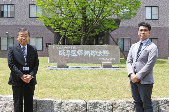  設置された石碑を囲む山岡学長（左）と福沢副会長＝可児市虹ケ丘の岐阜医療科学大可児キャンパスで