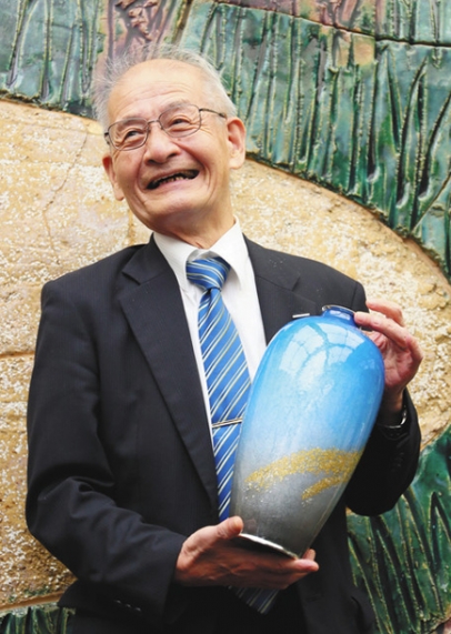 愛知県学術顕彰を受け、七宝焼の花瓶を手に笑顔の吉野彰名城大特別栄誉教授＝２日、愛知県公館で